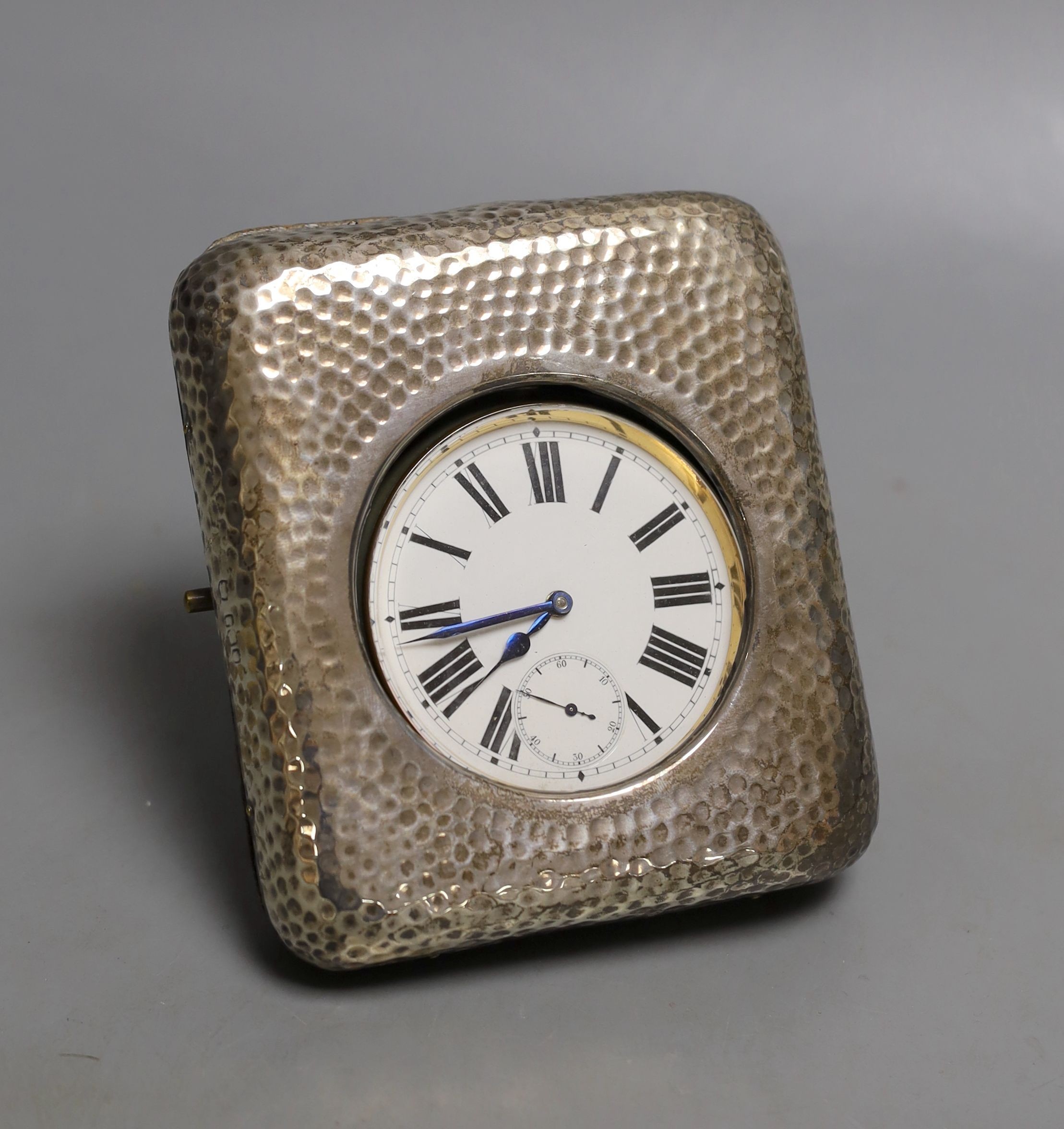 An early 20th century hammered silver mounted travelling watch case, marks rubbed, with keyless Goliath pocket watch.